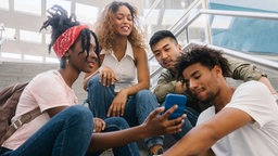 Junge Menschen schauen gemeinsam in ein Smartphone.