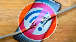 Smartphone mit zerrissenem Kabel und Schild mit durchgestrichenem WLAN-Symbol.