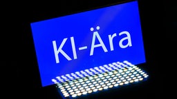 Das Wort "KI-Ära" ist auf einem Smartphone zu sehen, 05.12.2025.