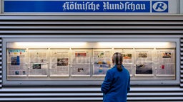 Frau liest das Zeitungsangebot der Kölnischen Rundschau. 