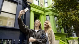 Touristen machen Selfies vor einer schwarzen Hausfassade in der Lancaster Road, Notting Hill, London, Großbritannien, 26.01.2019.