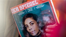 Eine Person hält die Spiegel-Ausgabe mit einem Artikel über Deep-'Fake-Verdacht in der Hand. 