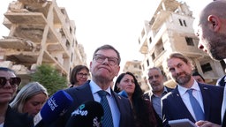 Johann Wadephul (M, CDU) steht vor zerstörten Häusern, Syrien, 4.11.2025.