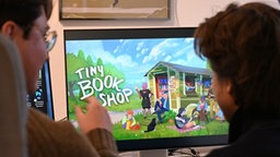 David Zapfe-Wildemann (l) und Raven Rusch sitzen vor einem Bildschirm, auf dem die Startseite des Spiels Tiny Bookshop zu sehen ist, 15.01.2026. 