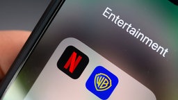 Smartphone mit App-Symbolen von Netflix und Warner Brothers.