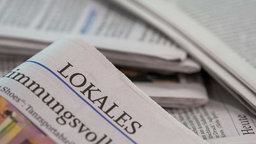 Eine Lokalzeitung wird über andere Zeitungen gehalten.