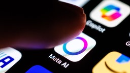 Ein Finger nähert sich dem Icon der Meta-AI-App auf einem Smartphone.