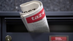 In einem Briefkasten steckt zuammengerollt eine Ausgabe der taz