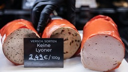 In einer Frischetheke liegen drei Sorten vegane Fleischwürste mit einem Preisschild, auf dem steht "Keine Lyoner"