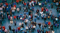 Sicht von oben auf viele Menschen, die auf einem Platz stehen
