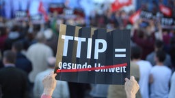 Schild mit Aufschrift TTIP gleich gesunde Umwelt, gesunde Umwelt ist durchgestrichen auf dem Schild