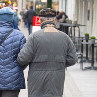 Ein älteres Paar geht Arm in Arm durch eine Einkaufsstraße