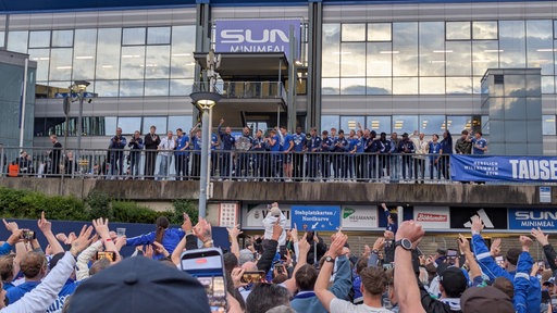 Das Schalke-Team steht vor der Arena und feiert mit seinen Fans