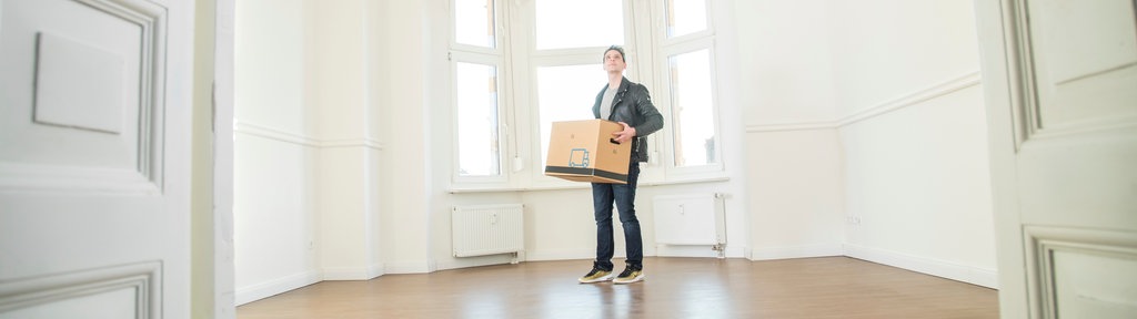 Ein Mann mit Umzugskarton in einer leeren Wohnung