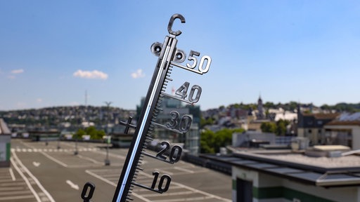 Im Vordergrund ein Thermometer vor der Kulisse der Stadt Siegen