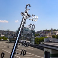 Im Vordergrund ein Thermometer vor der Kulisse der Stadt Siegen