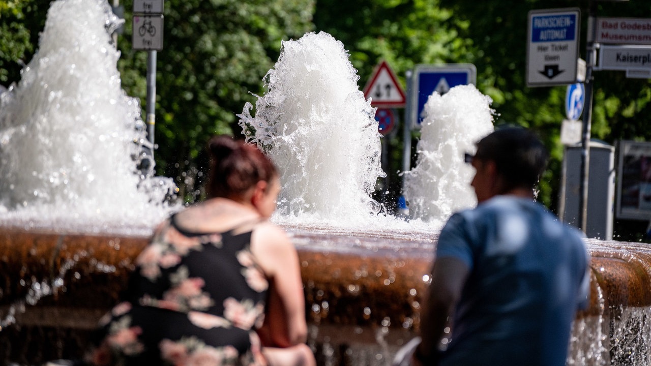 Zwei Personen sitzen an einem Brunnen