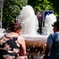 Zwei Personen sitzen an einem Brunnen
