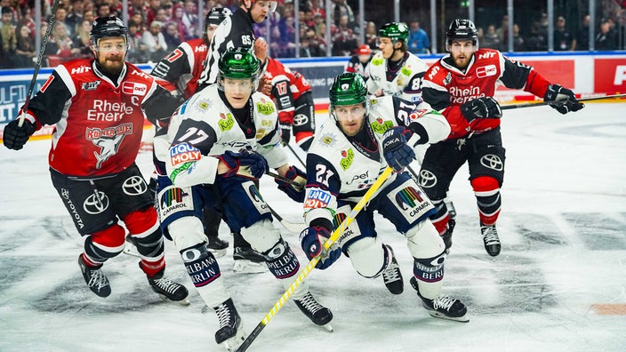 Moritz Müller und Robin van Calster versuchen zwei Spieler der Eisbären Berlin einzufangen