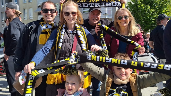 Männer, Frauen und Kinder tragen Trikots und Schals der Krefeld Pinguine