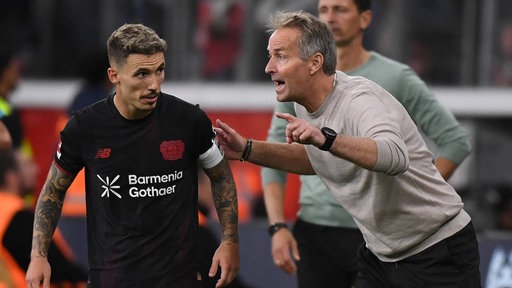 Bayer Leverkusens Trainer Kasper Hjulmand (v. r.) im Gespräch mit Alejandro Grimaldo