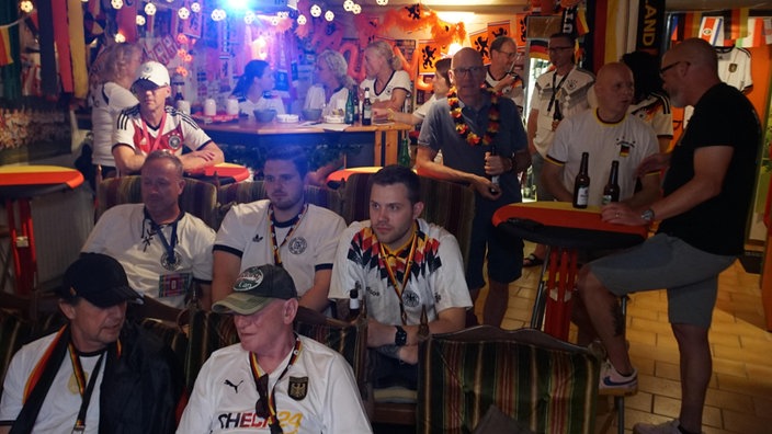 Fans schauen Fußball in einem bunt dekorierten Keller