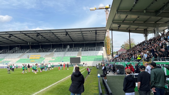 Die Mannschaft des SC Preußen Münster steht auf dem Rasen vor den Fans auf der Tribüne.
