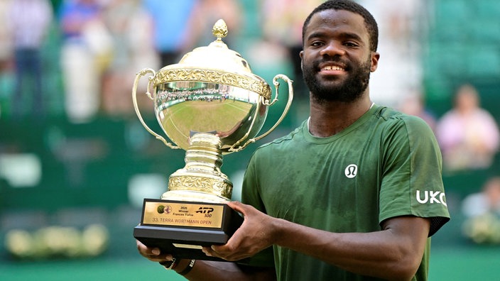 Frances Tiafoe posiert beim ATP-Turnier in Halle mit der Sieger-Trophäe