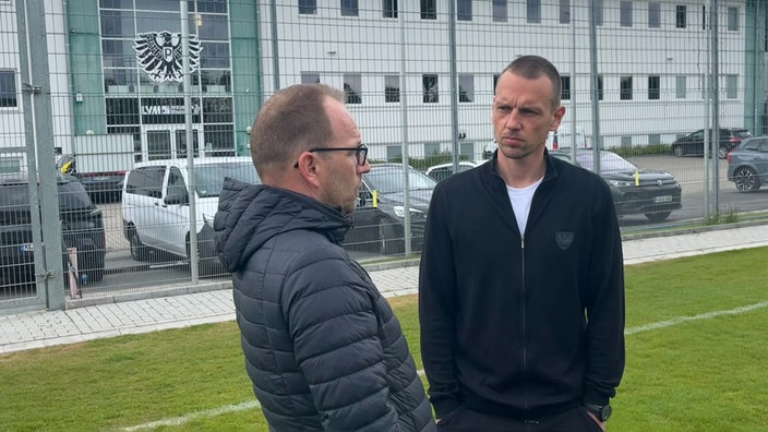 Ole Kittner im Gespräch mit Pressesprecher Marcel Weskamp auf einem Fußballplatz