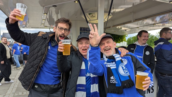 Schalke-Fans jubeln vor einem Bierstand.