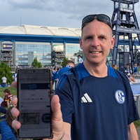 Schalke-Fan Sascha Walmsley zeigt stolz das Ticket, dass er geschenkt bekommen hat.