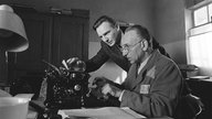 Film-Szene aus "Schindlers Liste": Schindler (Liam Neeson, l.) und sein jüdischer Buchhalter Itzhak Stern (Ben Kingsley) stellen eine Liste von über 1.100 jüdischen Arbeitern zusammen