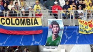 Kolumbianische Fußballfans haben am 15.6.1998 auf den Traversen des Stade Gerland von Lyon das Bild des einstigen kolumbianischen Fußballers Andres Escobar aufgehängt. Sie gedenken damit des Abwehrspielers, der beim WM-Turnier vor vier Jahren in den USA im Spiel gegen die Gastgeber ein Eigentor erzielte und dafür nach seiner Rückkehr in seine Heimat in Medellin auf offener Straße erschossen wurde.