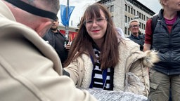 Eine Frau lächelt in die Kamera, während sie sich tätowieren lässt.