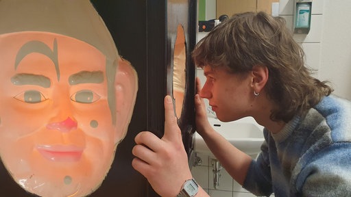 Der 19-jährige Nils Heidbüchel schaut in einen Kasten rein, der die Erfahrung einer Schizophrenie simulieren soll.