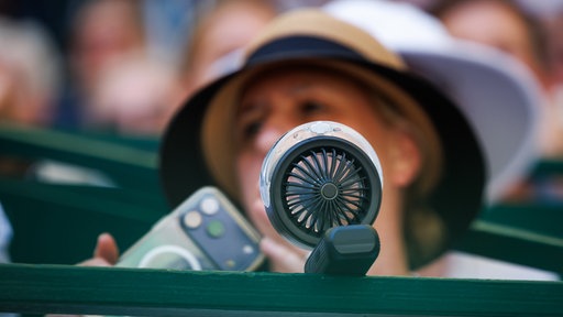 Eine Zuschauerin nutzt einen Gesichtsventilator in einer Loge auf dem Centre Court