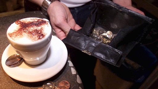 Ein Kellner hält seine Geldbörse auf, um einen Cappuccino abzukassieren 