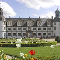 Großer Schlossgarten vor einem schwarzen und weißen Schloss.