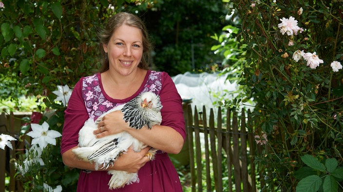 Jenny Slupkowskimit einem Huhn auf dem Arm. 