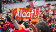 Nahaufnahme einer feiernden Menschenmenge. Jemand hälft ein Karnevals-Embleme mit der Aufschrift "Alaaf!" hoch