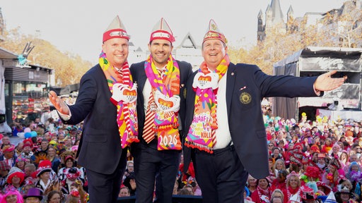 Das Kölner Dreigestirn mit Niklas Juengling (Prinz Niklas I.) gemeinsam mit Clemens von Blanckart (Bauer Clemens) und Stefan Blatt (Jungfrau Aenne) auf der Bühne beim Sessionsauftakt und Beginn der Karnevalssession 2025-2026 auf dem Kölner Heumarkt.