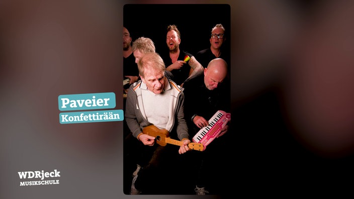 Die Band sitzt in einem engen Studio und spielt auf Kinderinstrumenten