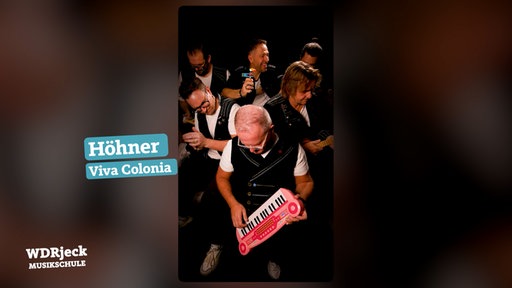 Die Band sitzt in einem engen Studio und spielt auf Kinderinstrumenten