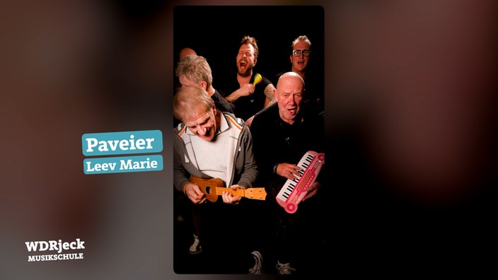 Die Band sitzt in einem engen Studio und spielt auf Kinderinstrumenten
