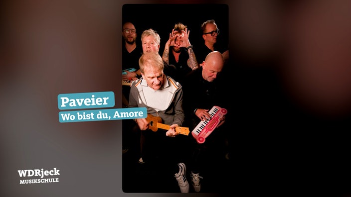 Die Band sitzt in einem engen Studio und spielt auf Kinderinstrumenten