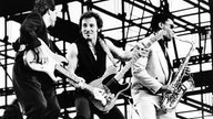 Bruce Springsteen 1988 in Berlin auf der Bühne mit Gitarrist Nils Lofgren (links) und Saxophonist Clarence Clemons (rechts).