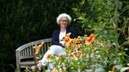 Ute Brehm auf einer Bank im Garten. 