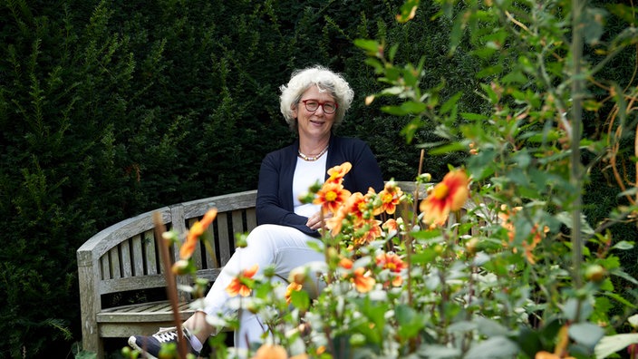 Ute Brehm auf einer Bank im Garten. 