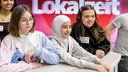 Drei Mädchen lachen vor dem Schriftzug „Lokalzeit“