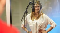 Schülerin steht mit Kopfhörer vor einem Mikrofon im WDR STUDIO ZWEI